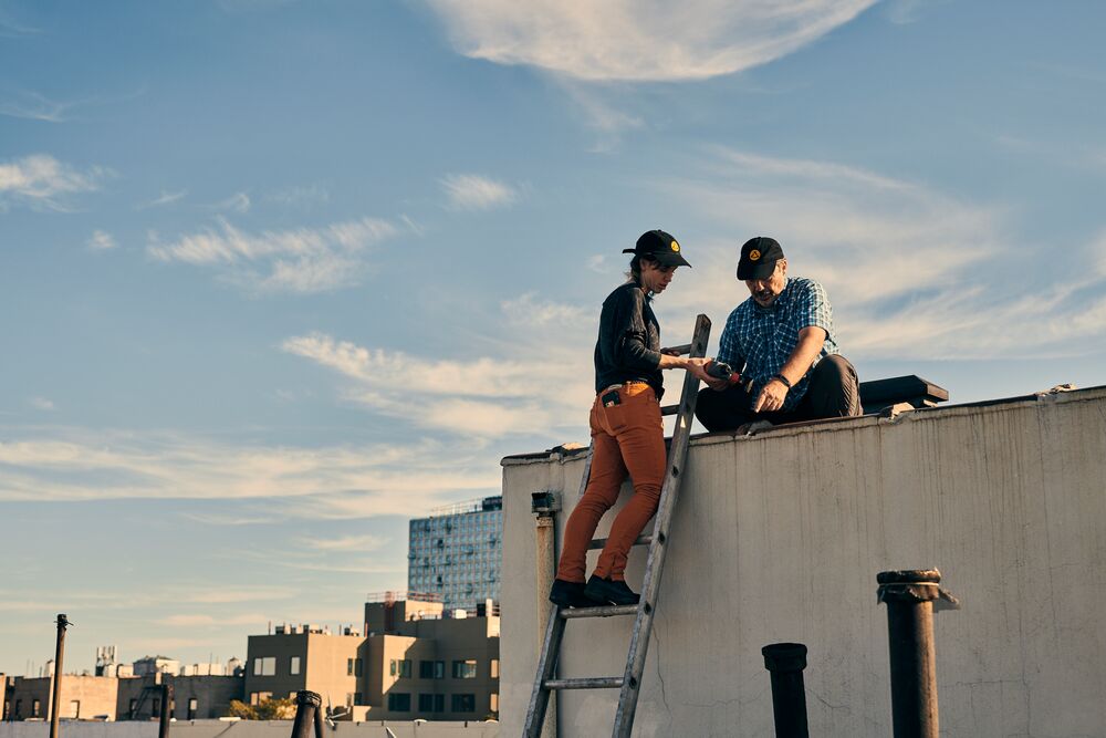 Two men standing on a rooftop, gazing intently at an unseen object