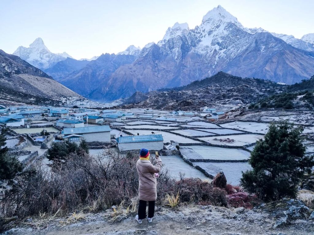 Woman capturing scenic mountain village with camera.