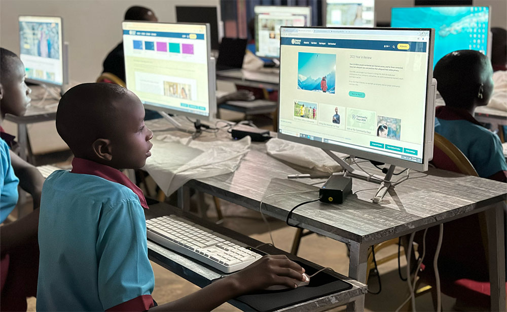 A child in a blue shirt sits at a computer.