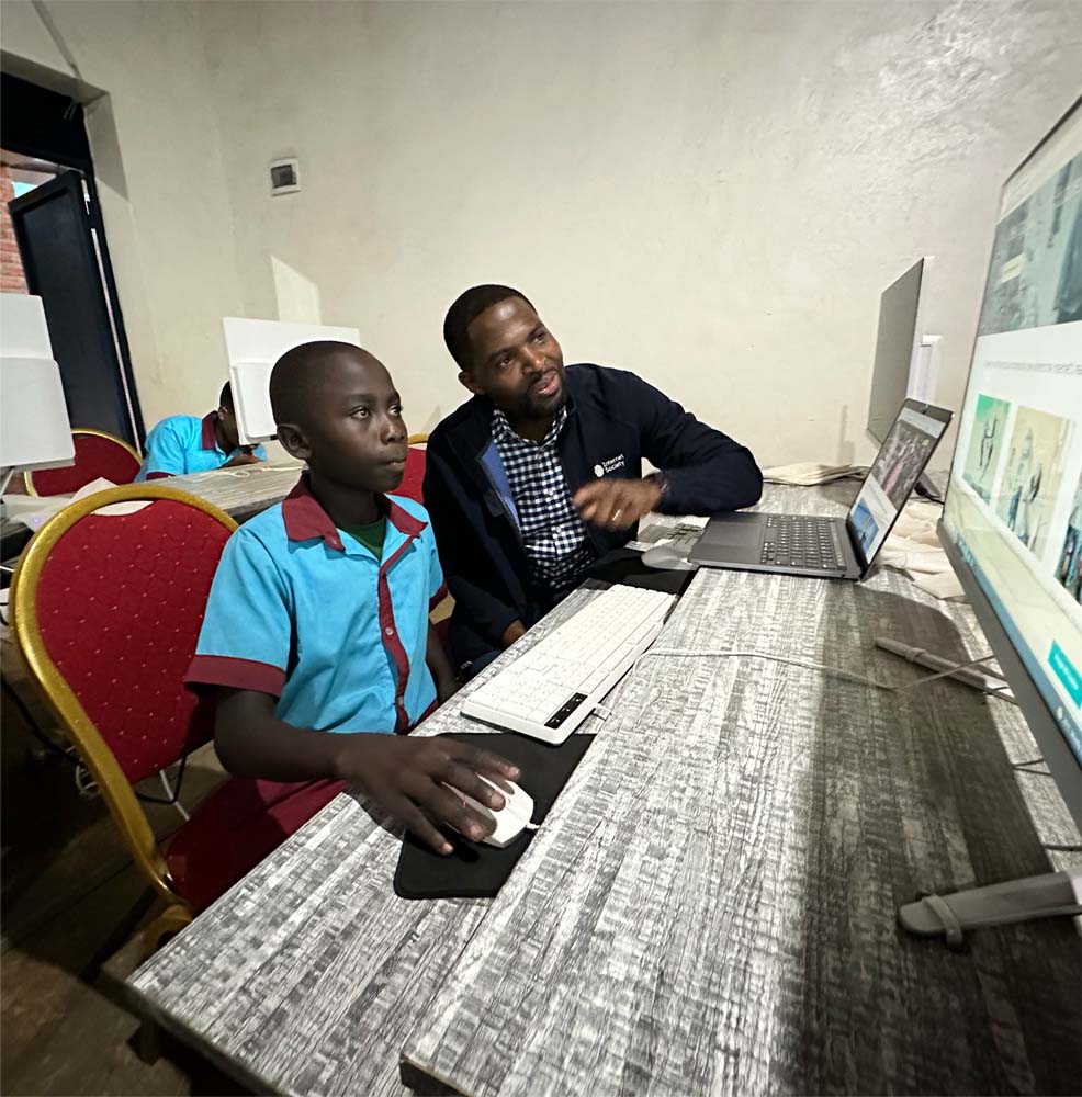 A man and boy look at a computer at an Internet Access Center in Rwanda.