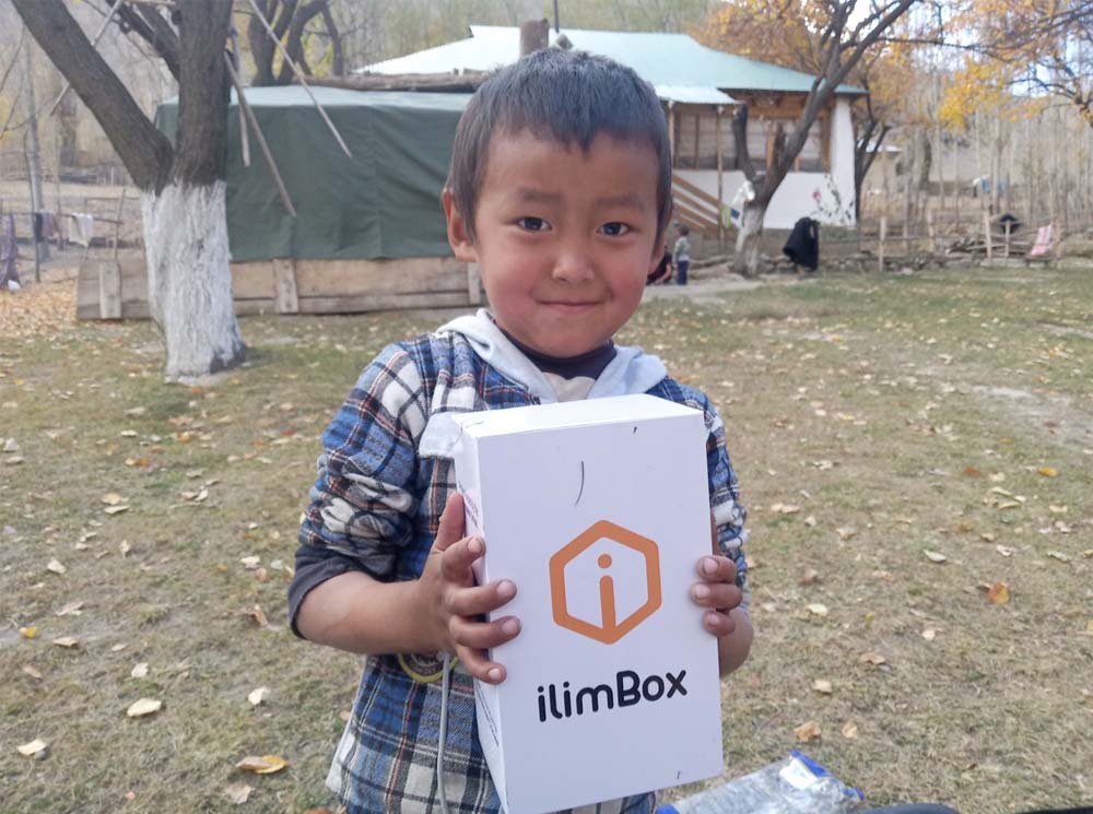 Un enfant tient une boîte blanche sur laquelle on peut lire : ilimBox