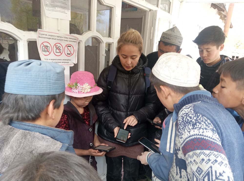 People holding phones huddle.