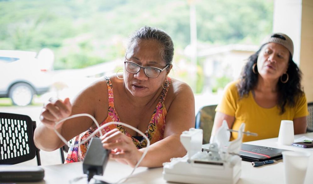 Two women sit at a table while working on Internet infrastructure.