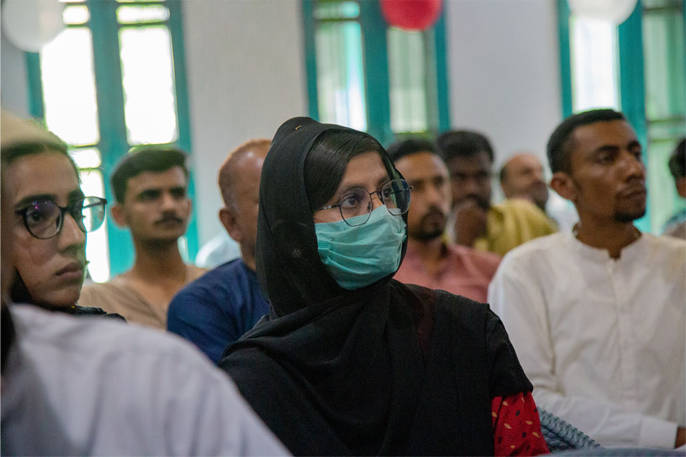 A woman wearing a mask sits in a group