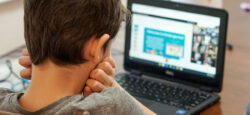 The back of a kid's head as he looks at a computer.