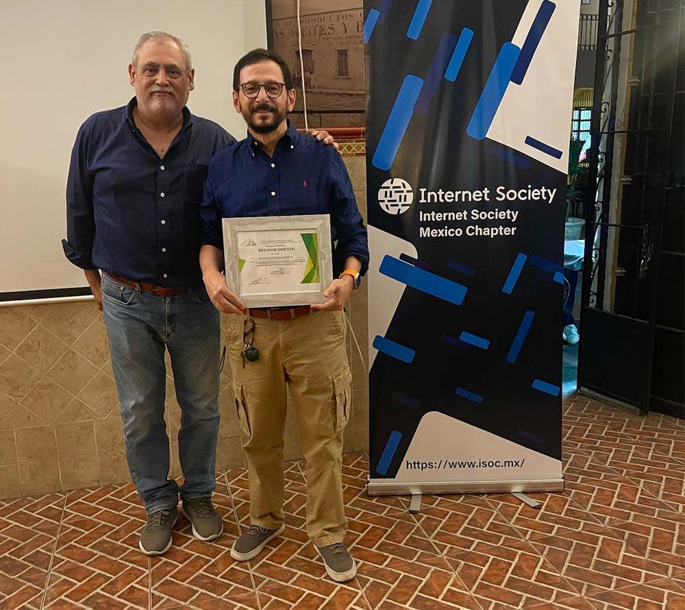 Two men stand together next to an Internet Society Mexico Chapter sign