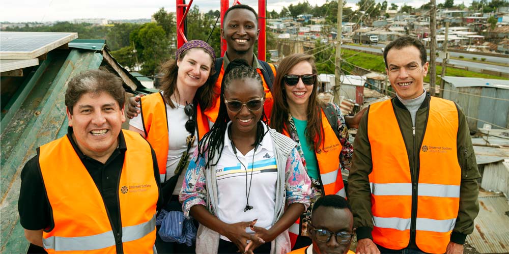 Ruth Njeri stands with several people in orange Internet Society vests