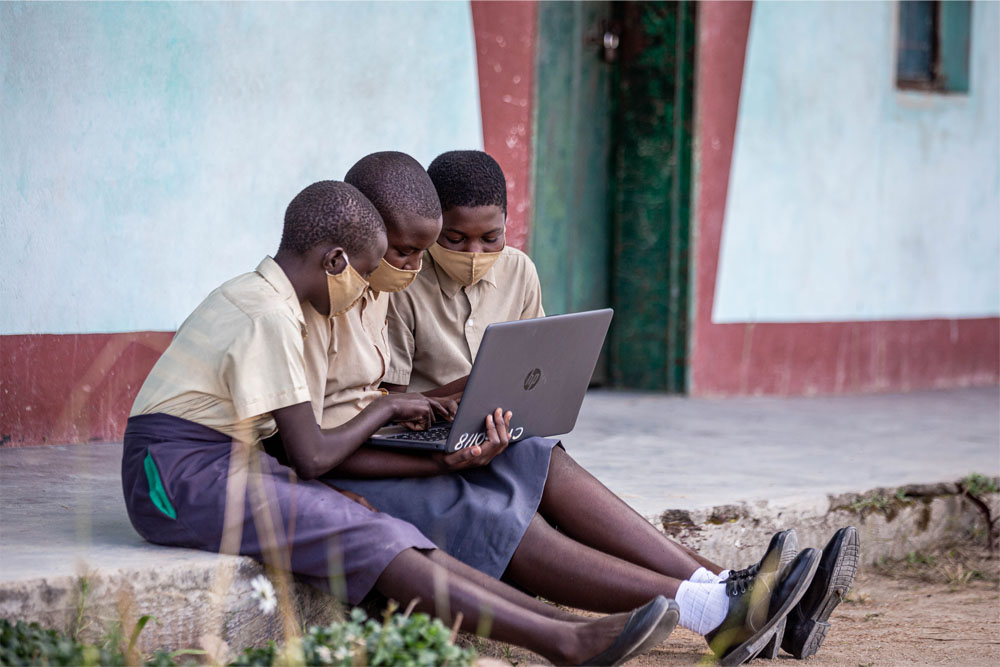 Three girls sit and look at a laptop