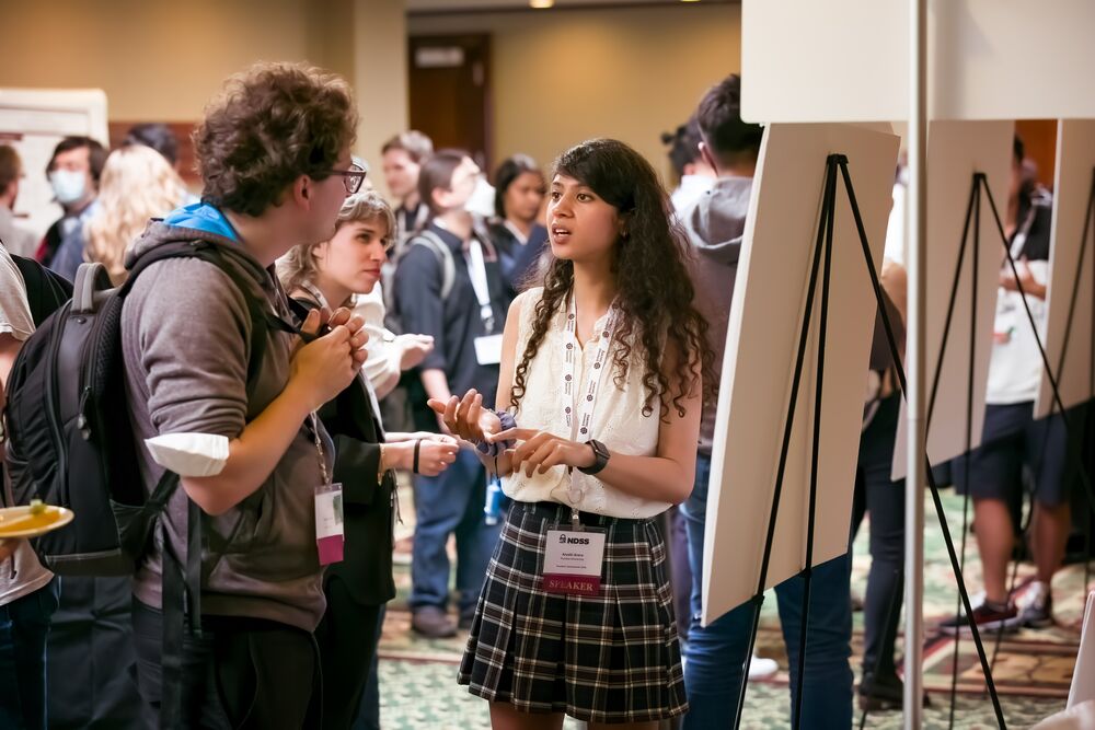 Three people stand and converse at NDSS